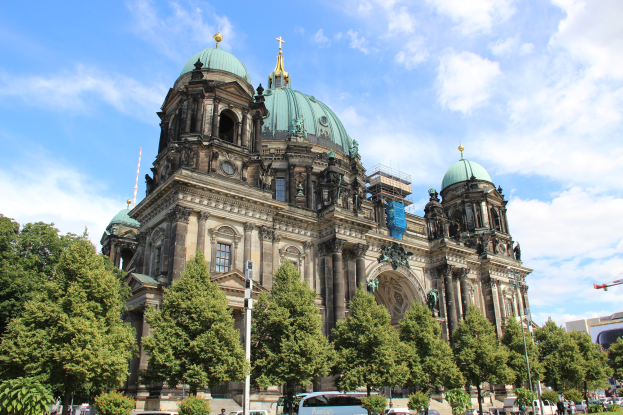 Große Kuppelkathedrale mit klassischer Architektur, umgeben von Bäumen und städtischen Elementen unter einem bewölkten Himmel.