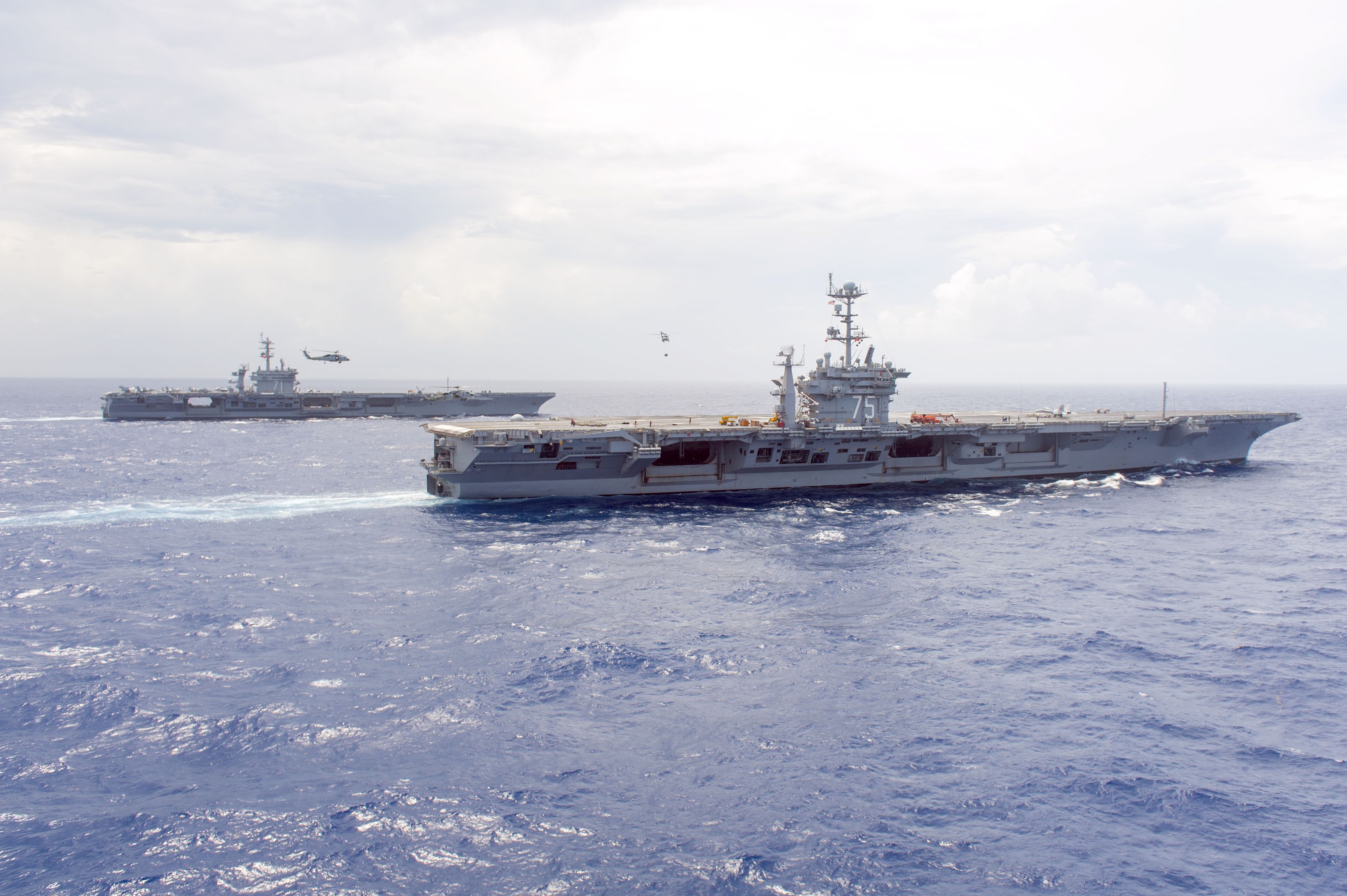 Zwei US-Navy-Flugzeugträger, USS George H.W. Bush (CVN-77) und USS Harry S. Truman (CVN-75), fahren in Formation durch die Arabische See bei bewölktem Himmel.
