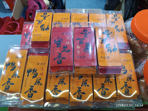 Ein Tisch voller verschiedener Lebensmittel, darunter Packungen, Schachteln und Taschen, mit einer Person im Hintergrund während eines chinesischen Neujahrsfestes.