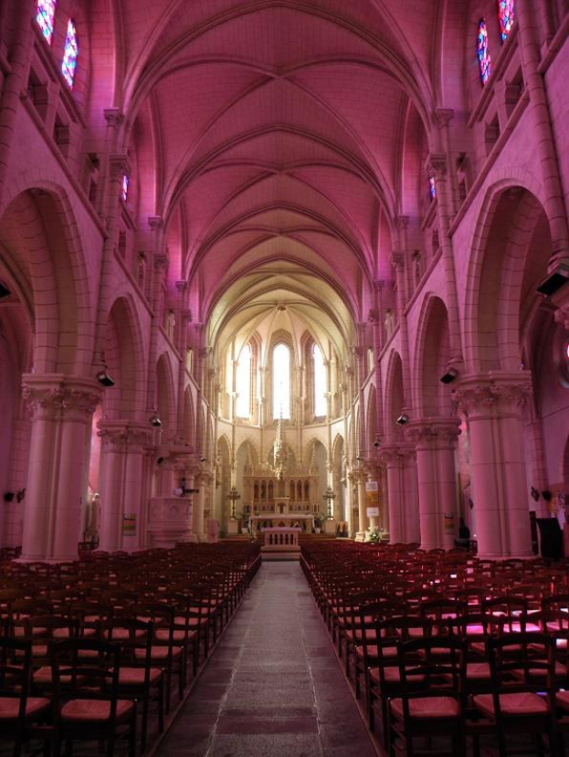 Innere eines Kirchenschiffs mit Stuhlreihen, Säulen, Buntglasfenstern und brennenden Kerzen, eingerichtet für eine Hochzeitszeremonie.