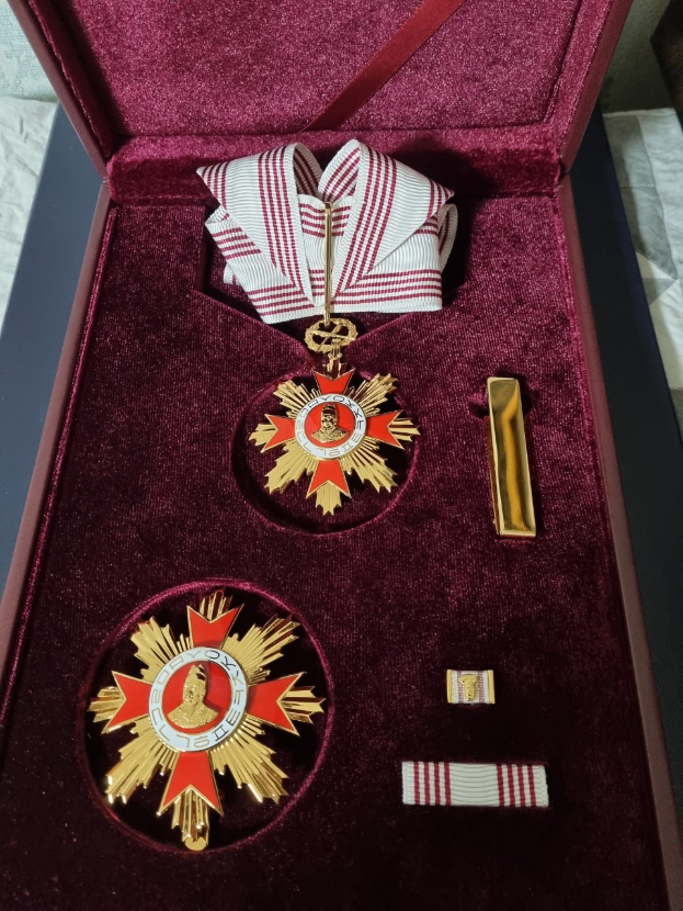 Roter Karton mit der Medaille des Sterns der Russischen Föderation mit einem roten und weißen Band, auf einer weißen Oberfläche platziert.