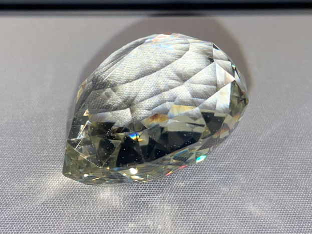 Ein 0,50 Karat natürlicher, intensiver, grünlich-gelber Diamant auf einer weißen Oberfläche.