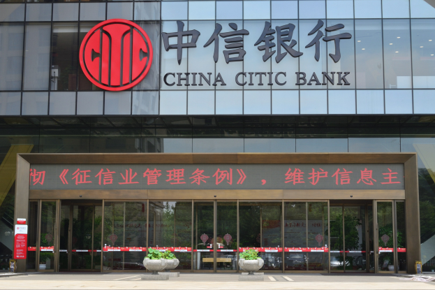 Außenansicht des China Citic Bank-Hauptsitzes in Shanghai mit Glaswänden, -türen, Text auf dem Gebäude, Topfpflanzen und einer Straße unten.