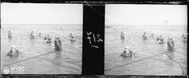 Schwarzes und weißes stereoskopisches Bild von Menschen, die im Wasser schwimmen, mit einem Seil im Vordergrund und Himmel im Hintergrund, mit einem Wasserzeichen, das es als stereoskopische Ansicht der Taufe Jesu darstellt.