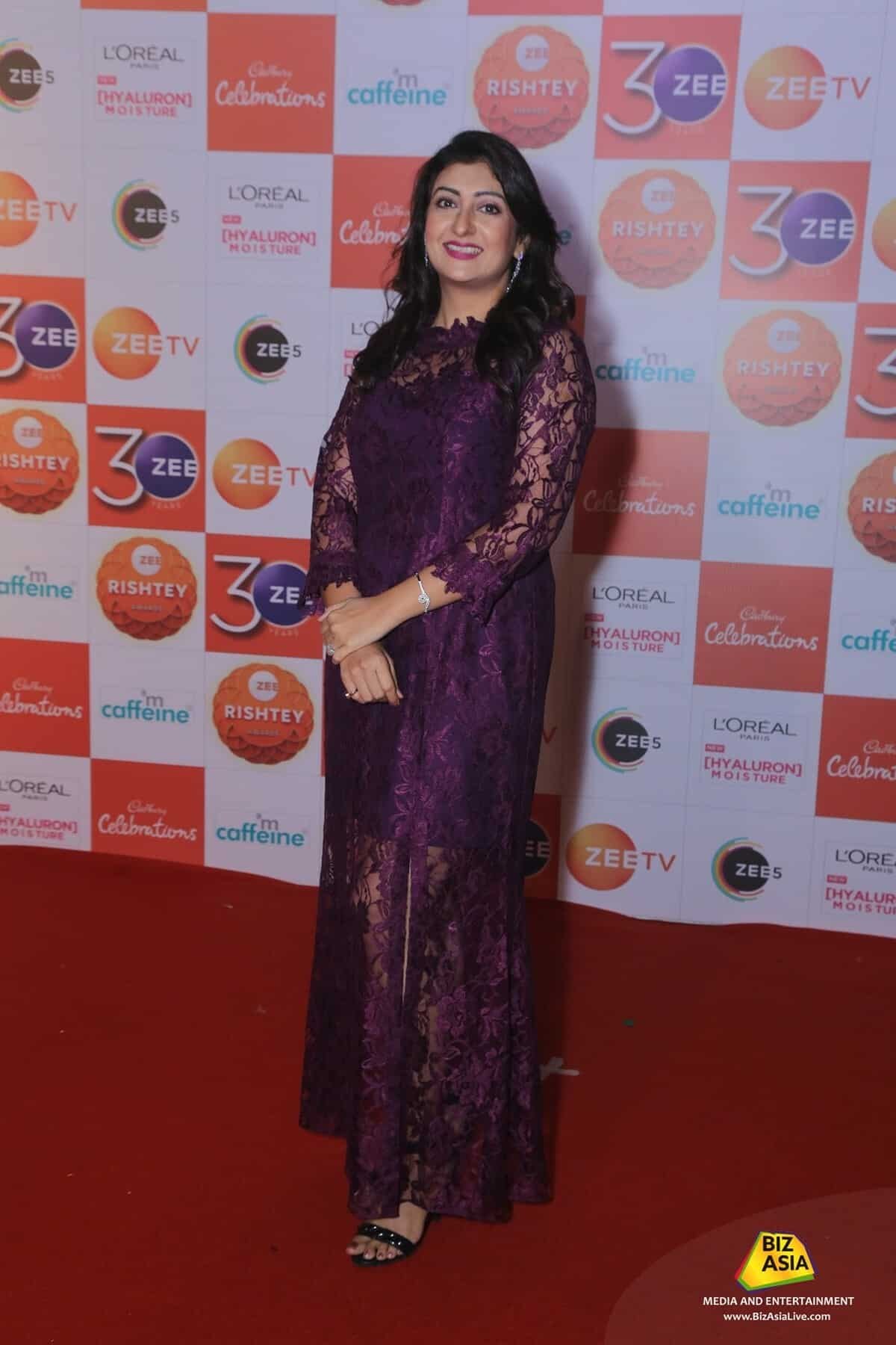 A woman in a purple dress stands on the red carpet at the Zee Cine Awards 2017, with a backdrop displaying the event's name and a watermark in the corner.