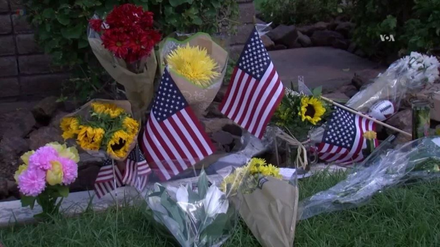 Blumen und amerikanische Flaggen vor einem Haus auf dem Boden plaziert.