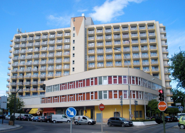 Großes gelbes Gebäude mit vielen Fenstern in Berlin, Deutschland, umgeben von Straßeninfrastruktur und Fahrzeugen, verfügbar zur Miete.