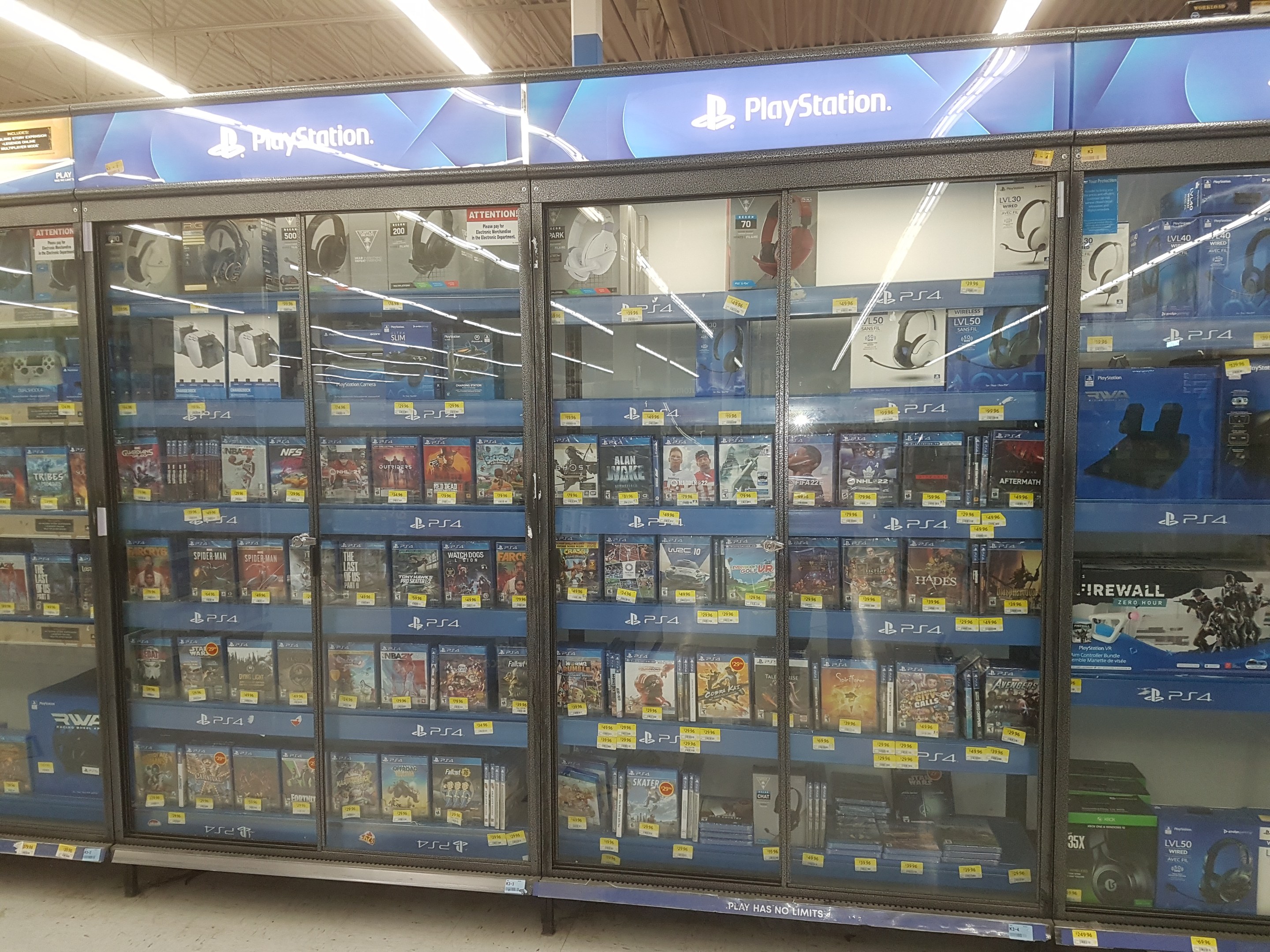 A PlayStation Store aisle with various video games displayed on shelves under ceiling lights.