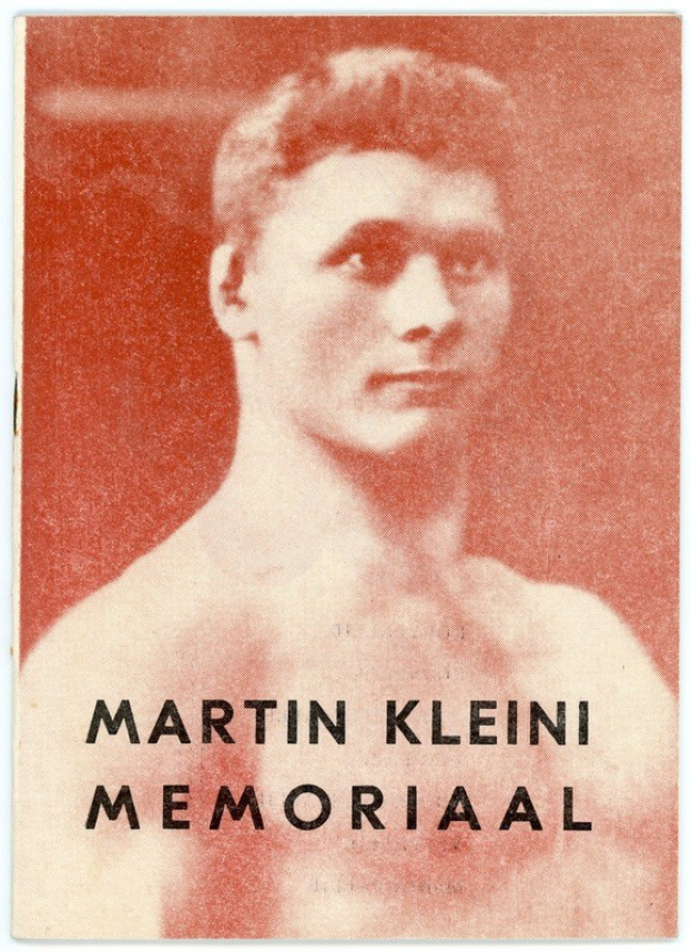 Ein Schwarz-Weiß-Foto von Martin Klein Memorial, ein Mann mit zurückgekämmtem Haar, der ein weißes Hemd und dunkle Hosen trägt und direkt in die Kamera blickt.