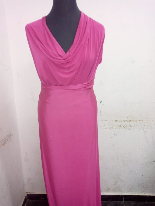 Ein pinkfarbenes Kleid, das an einer Schaufensterpuppe gegen eine kahle Wand hängt, mit einem Teil des Bodens sichtbar.