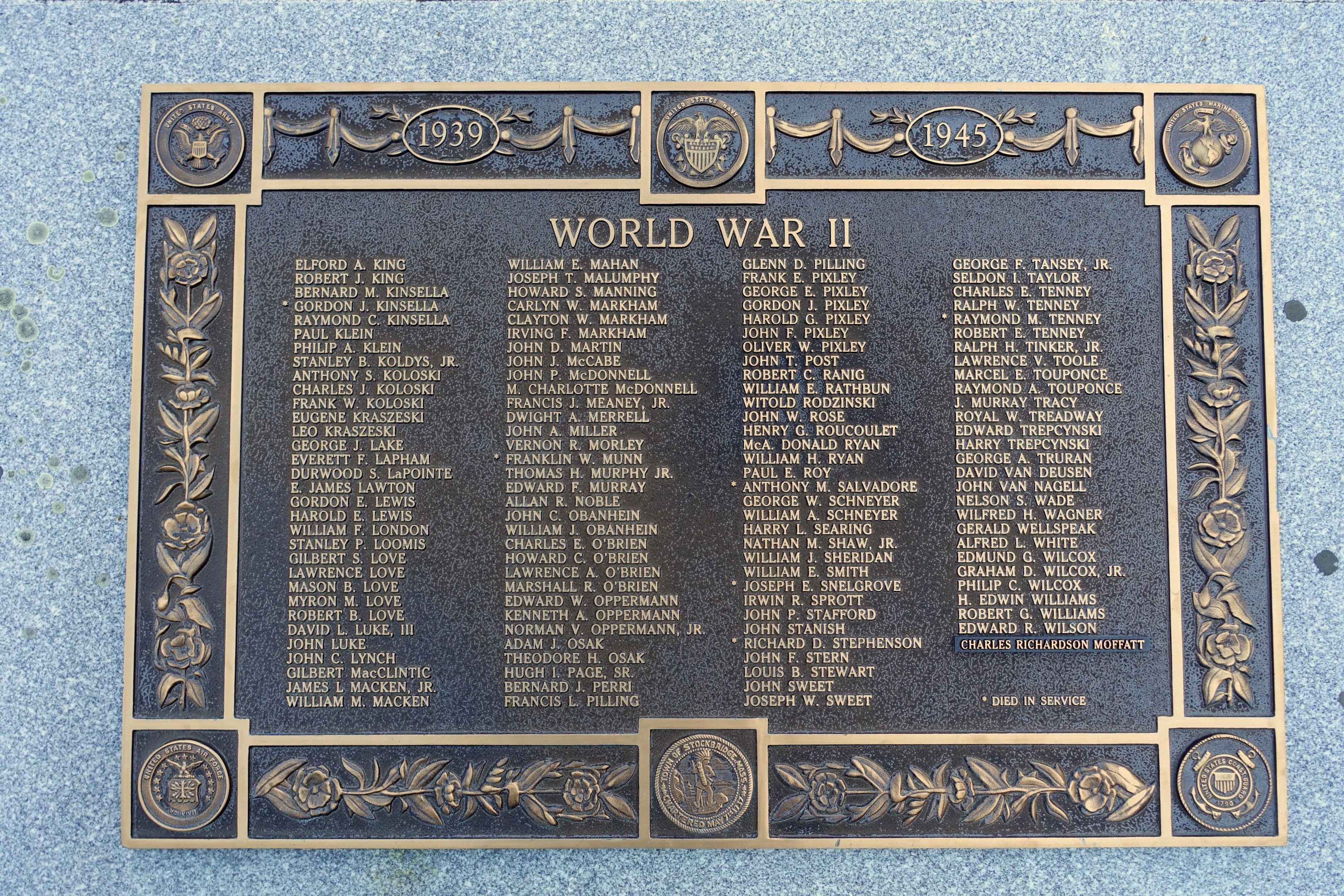 Steintafel an der Außenseite eines Gebäudes mit der Inschrift "Weltkrieg II".