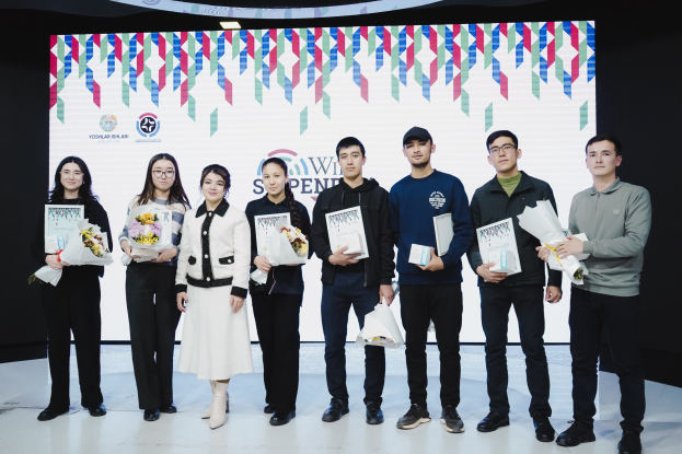 Gruppe von Menschen auf einer Bühne mit Bücher und Blumensträußen, im Hintergrund ein Bildschirm mit der Aufschrift "Yogyakarta International School of Science and Technology."