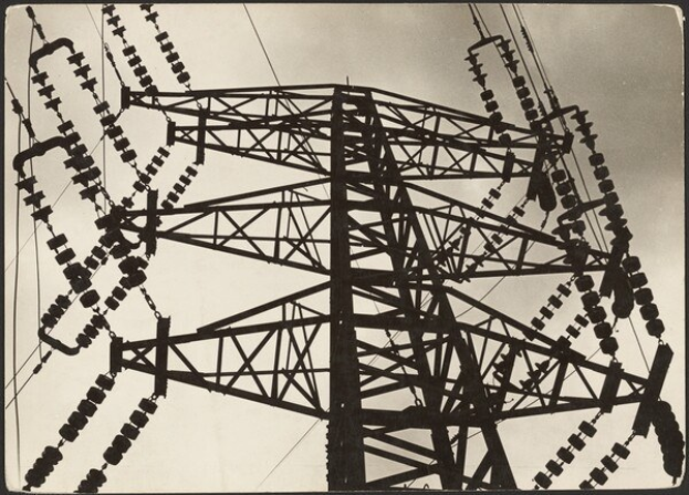 Schwarz-weiß-Foto eines Hochspannungsfreileitungsmastes mit Drähten vor einem Himmel, mit Text unten.