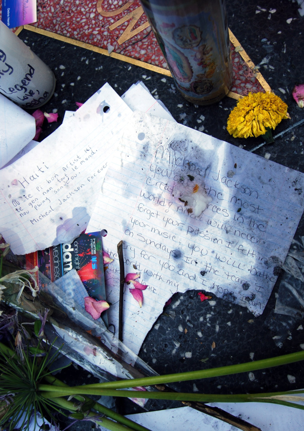 Gedenkstätte auf dem Hollywood Walk of Fame mit einem Strauß Blumen, Papieren, Büchern und einem Glas auf dem Boden, die Blumen blühen in voller Pracht.
