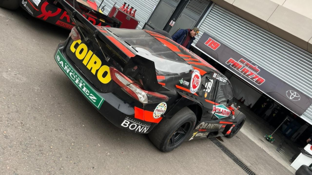 Gruppe von Rennwagen vor einem Gebäude mit "Le Mans 2019"-Banner geparkt, Menschen in der Nähe.