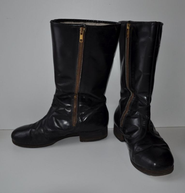 Schwarze Lederstiefel mit silbernen Reißverschlüssen auf einer weißen Oberfläche, mit einem glänzenden Finish.