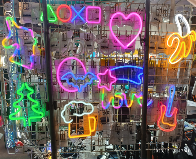 Neon-Schilder in verschiedenen leuchtenden Farben hängen von der Decke eines Ladens und erzeugen eine lebendige und einprägsame Auslage.