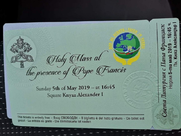 Schwarze Fläche mit einer Karte, auf der ein Text und ein Logo mit der Aufschrift "Heilige Messe in Anwesenheit von Papst Franziskus" zu sehen sind.