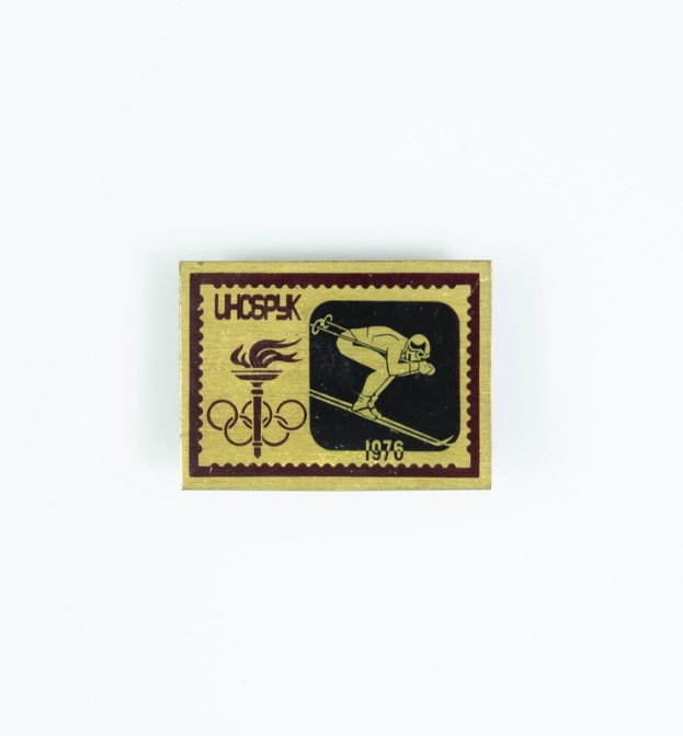 Marke mit einem Skifahrer mit dem Text "1976 Winter Olympics" und einem Ereignis-Logo auf einem weißen Hintergrund.