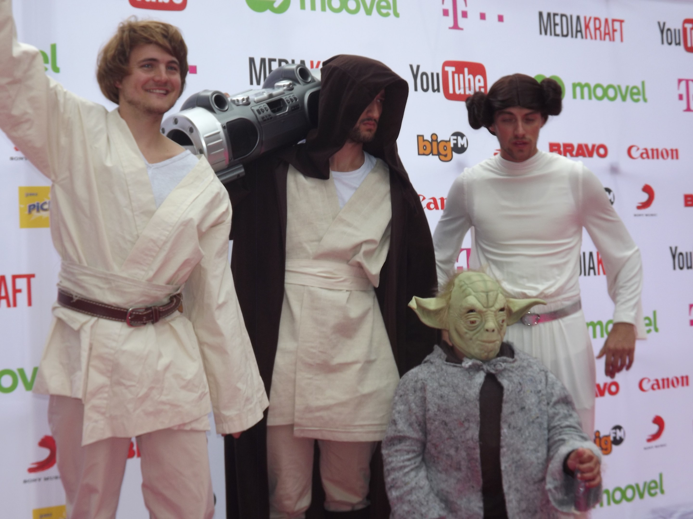 A group of people in Star Wars costumes posing on a red carpet with a banner in the background.