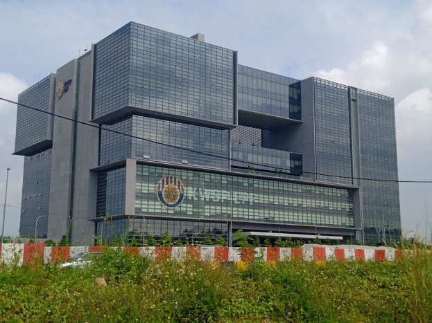 Großes Gebäude mit zahlreichen Fenstern, identifiziert als Hauptsitz der Central Bank of India, umgeben von Grünflächen, Straßeninfrastruktur und einem bewölkten Himmel.