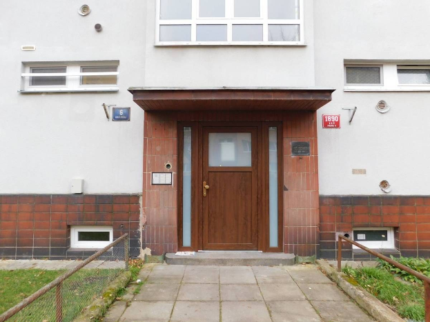 Zweizimmer-Doppelhaushälfte mit weißer Fassade, brauner Tür und Fenstern, Metallzaun, Gras, Weg und Schilder an der Wand, zum Verkauf in St Johns Court, St Johns Road, Luton.