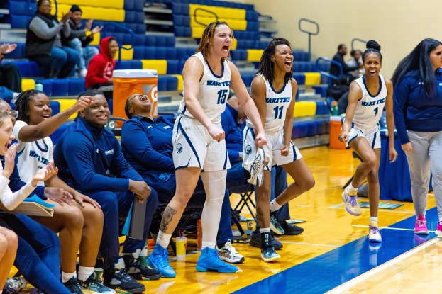 Eine Gruppe von Frauen-Basketball-Spielerinnen auf einem Feld mit Zuschauern im Hintergrund.