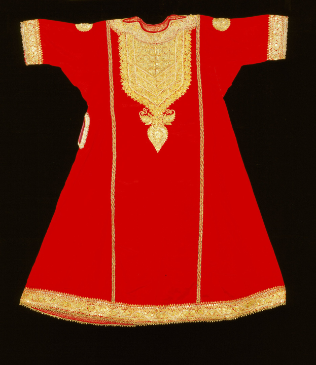 Ein rotes Kleid mit goldener Stickerei vor schwarzem Hintergrund.
