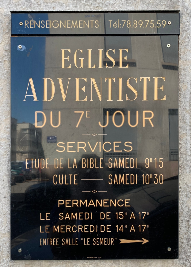 Poster on a building wall with text "Eglise Adventiste du 7e jour Services."
