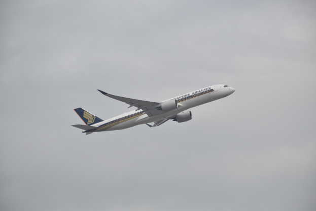 Airbus A330-300 der Singapore Airlines im Flug mit weißer, blauer und gelber Lackierung vor grauem Himmel.