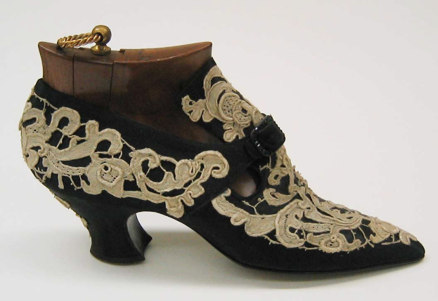 Schwarze und goldene bestickte High Heels auf einem weißen Hintergrund.