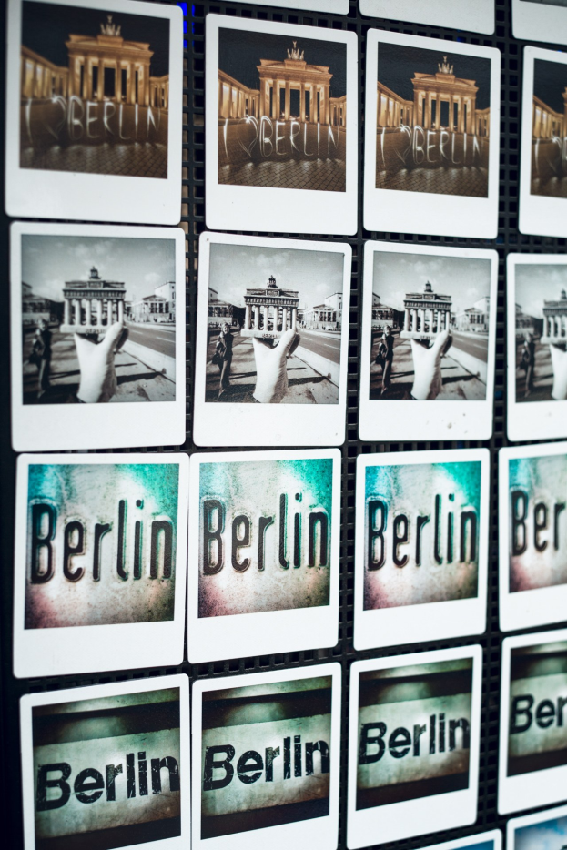 Collage von Berlin-Fotos an einer Wand, einschließlich des Brandenburger Tors und des Wortes "Berlin."