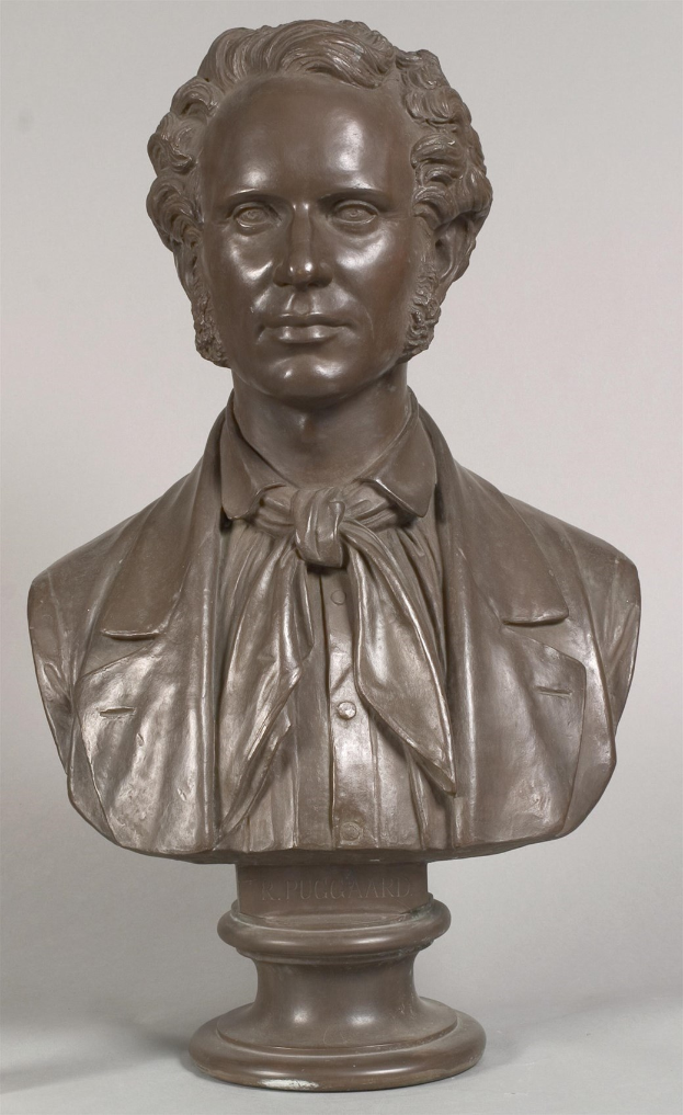 Eine Bronzebüste von Ludwig van Beethoven mit einer Fliege, vor einem weißen Hintergrund.