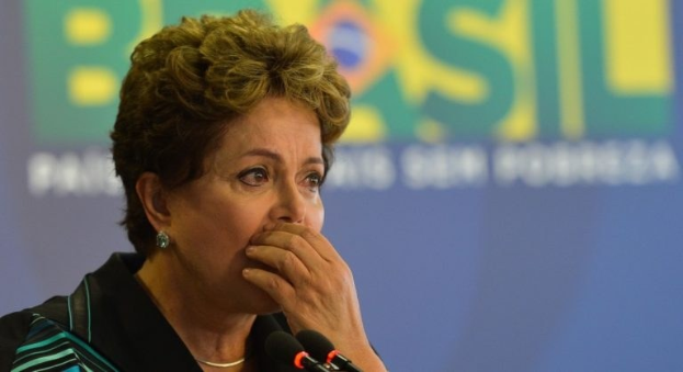Brasiliens Präsidentin Dilma Rousseff spricht bei einer Pressekonferenz in Rio de Janeiro und steht vor einer Tafel mit Text und mehreren Mikrofonen.