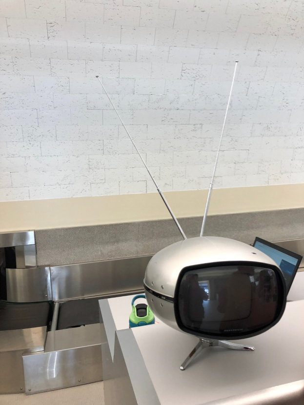 Alter Fernseher auf einer Arbeitsplatte neben einem Laptop, mit einer Wand im Hintergrund.