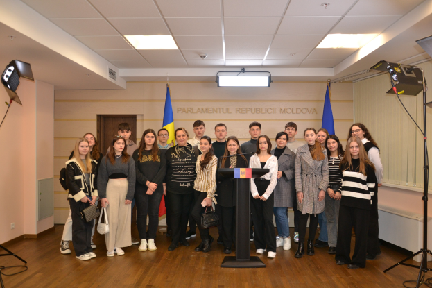 Gruppe von Menschen vor einem Podium mit einem Mikrofon auf dem Moldova-Jugendkongress 2018, umgeben von Fahnen, einer Wand mit Text, einer Tür, einer Decke mit Deckenleuchten und Leuchtenständern.