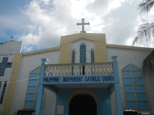 Die Unabhängige Katholische Kirche der Philippinen in Cebu City, ein weißes und blaues Gebäude mit einem Kreuz darauf, umgeben von Bäumen und einem klaren blauen Himmel.