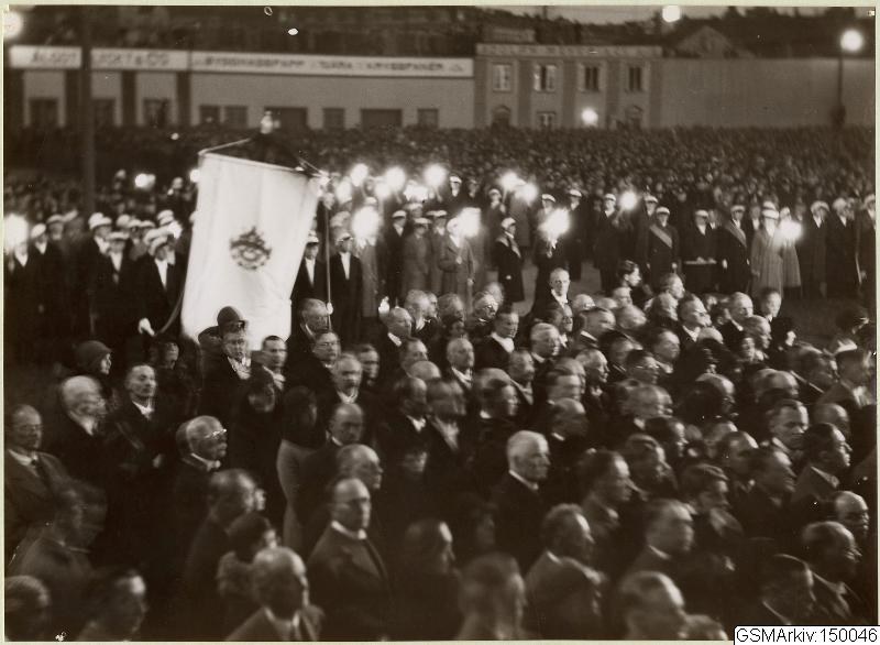 Schwarzes und weißes Foto einer großen Menschenmenge vor einem Gebäude, mit einer Person, die eine Flagge hält, in der Mitte, Polen und Lichter im Hintergrund und Text, der unten 'Gustav Klimts Rede an der Berliner Mauer' lautet.