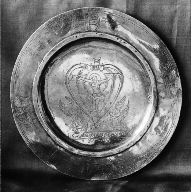 Schwarzes und weißes Foto eines silbernen Tellers mit einem Herzdesign und komplexen texturierten Mustern.