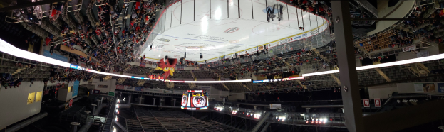 Eine große Indoor-Hockey-Arena mit Zuschauern in Reihen, umgeben von Geländern, Brettern und Beleuchtung, mit Treppen zum Sitzbereich.