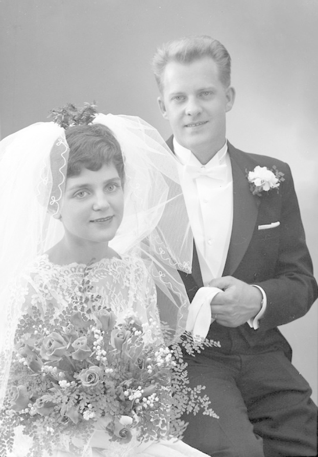 Schwarz-weiß-Foto eines Mannes in einem Smoking und einer Frau in einem weißen Hochzeitskleid mit einem Bukett.