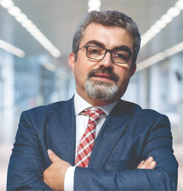 Ein Mann in Anzug und Krawatte mit verschränkten Armen, der eine Brille trägt und vor einem unscharfen Hintergrund steht, mit Text unten, der seine neue Rolle als Marketingchef angibt.