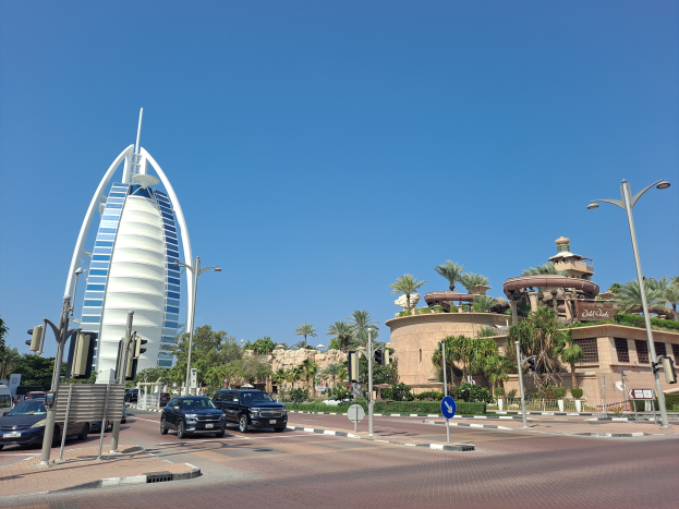 Luftaufnahme des Burj Al Arab Hotels in Dubai, UAE, mit Fahrzeugen, Straßeninfrastruktur, Grünflächen und umliegenden Gebäuden.