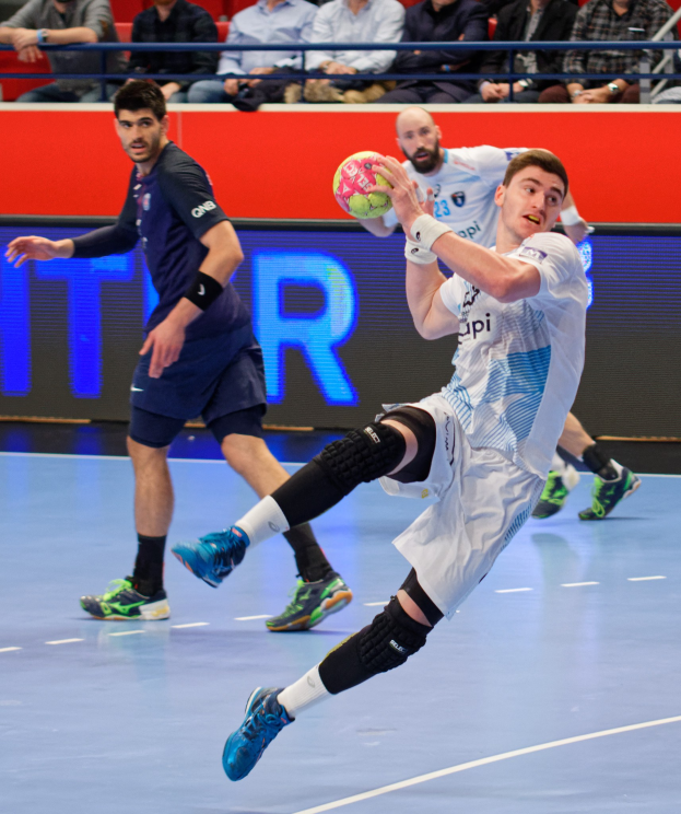 Männer spielen Handball auf einem Court während des Futsal-Weltmeisterschaft 2019, mit Zuschauern im Hintergrund und einer Anzeigetafel mit Veranstaltungstagen.