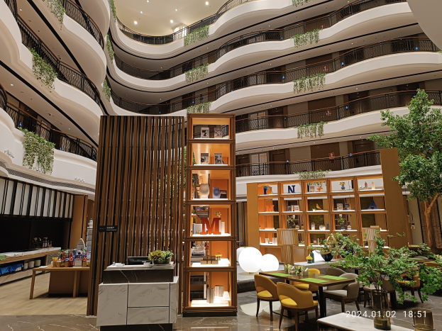 Großer Atrium mit Tischen, Stühlen, Topfpflanzen, Geländern und Beleuchtung im Inneren eines Dubai-Hotels.