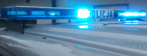 Polizeiauto mit blinkenden Lichtern an einer Wand geparkt.