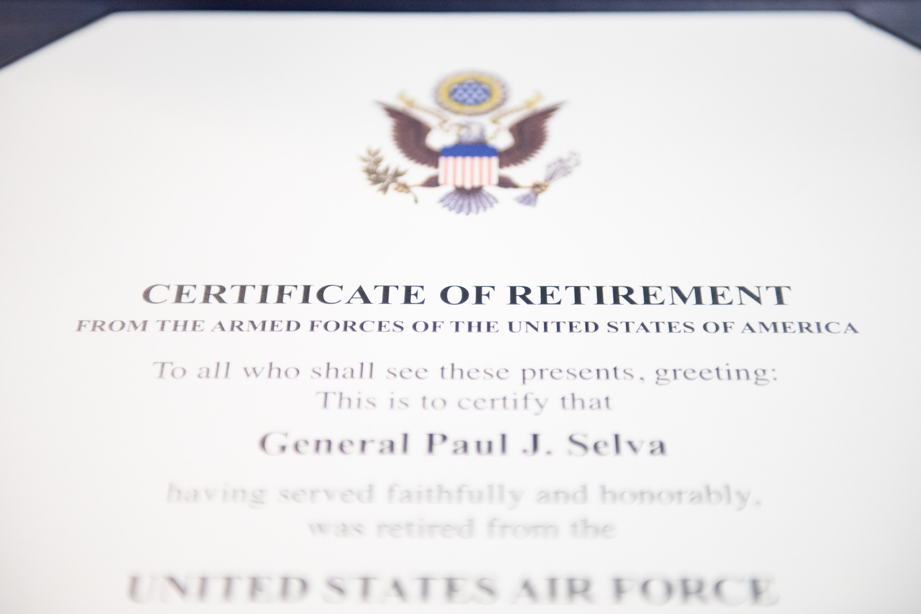 Rahmenurkunde für den Ruhestand der United States Air Force mit blauem Rand, mit einer schwarzen Textschrift und einem zentralen Schild-Logo mit einem Stern, einem Lorbeerkranz und einer 'Ruhestand'-Banderole.