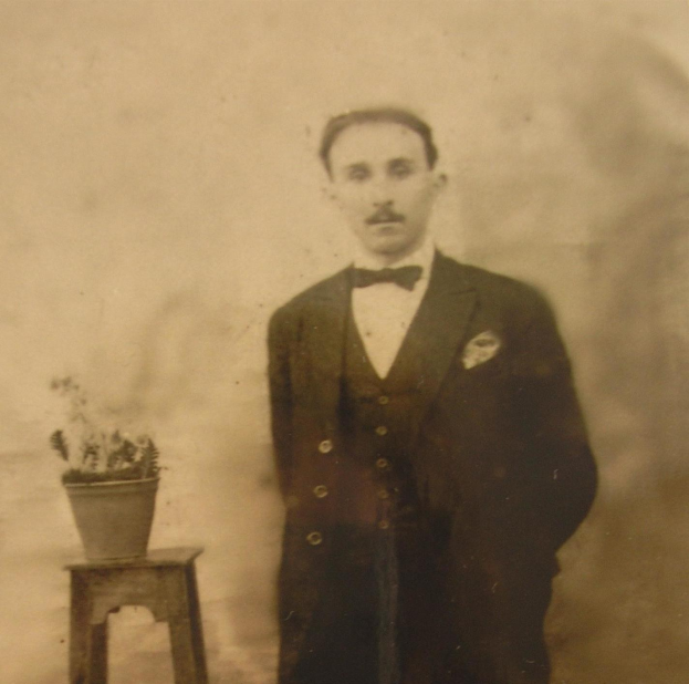 Schwarz-weiß-Foto eines Mannes in einem Smoking, der neben einem Topf mit einer Pflanze auf einem Hocker steht, beschriftet mit "Vater der Braut".