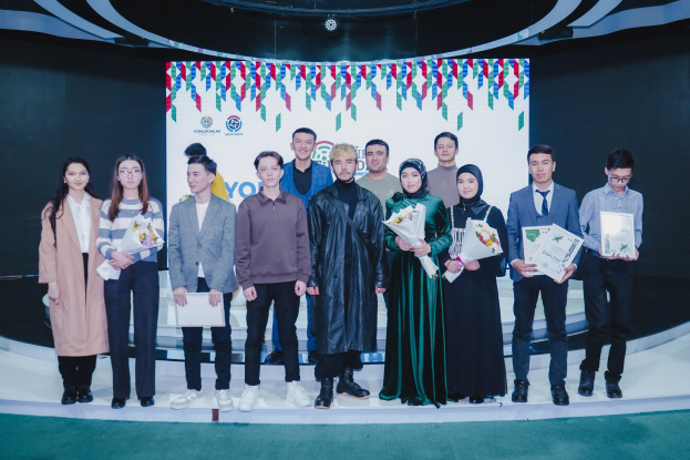 A group of people on a stage holding bouquets and certificates, with a backdrop reading "Youth Solar Awards 2019."