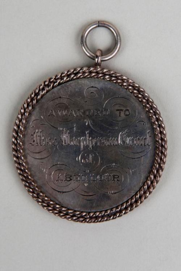 Silver round medal with black text "Awarded to the Metropolitan Council" on a decorative border, hanging from a rope.